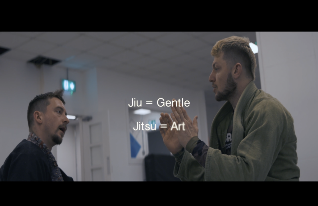 A photographic still from the short film Run Deep. The photo shows two men practising martial arts. The text overlay says: Jiu=Gentle, Jitsu = Art