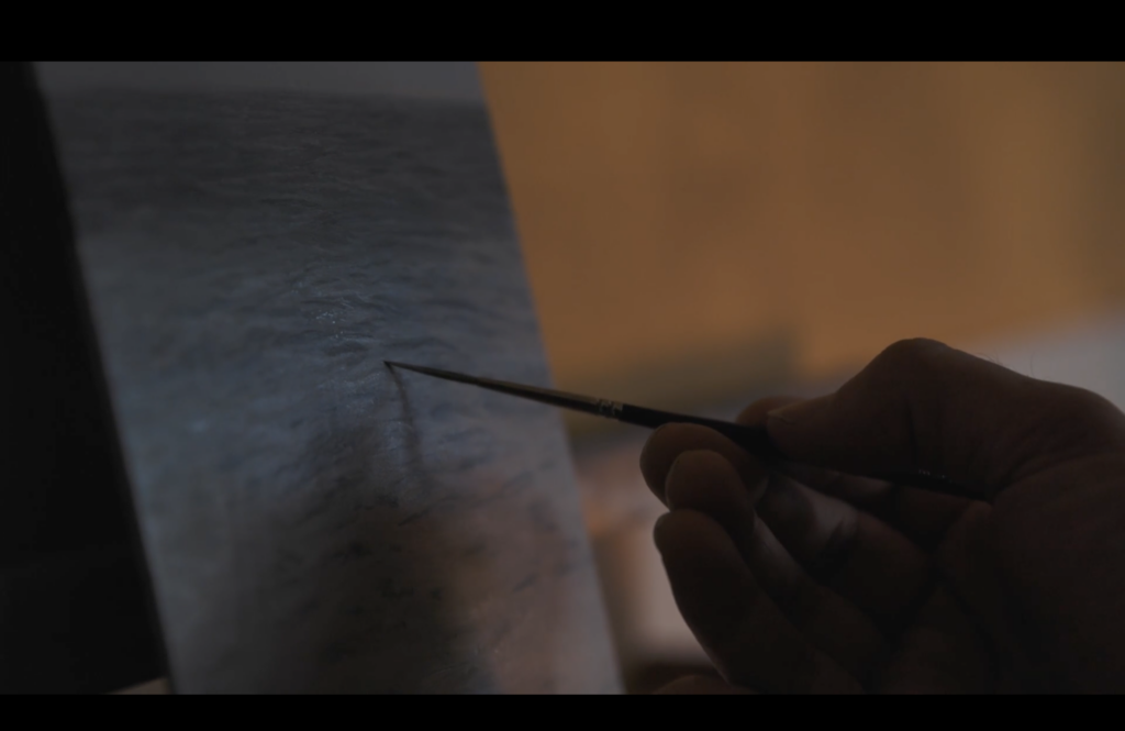 A photographic still from the short film The Artist. The photo shows the artist painting.